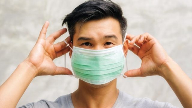 Man putting on a surgical mask | موسوعة الشرق الأوسط