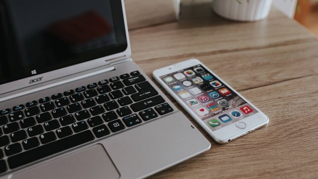 kaboompics Silver Acer laptop and a white Apple iPhone on a wooden desk | موسوعة الشرق الأوسط