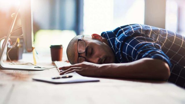 man asleep at desk tired and fatigued from stress | موسوعة الشرق الأوسط